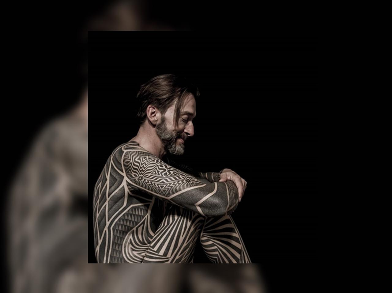 全身に幾何学柄タトゥーを入れた男性、ボディスーツを着用しているよう