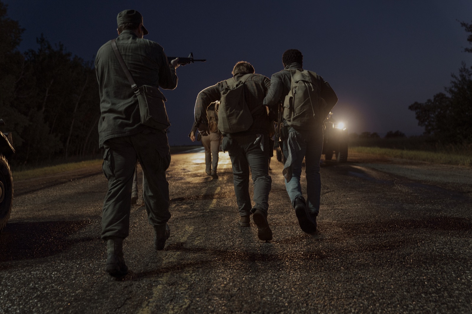銃を構えた兵士に見張られながら夜道を歩く『ロングウォーク』の参加者