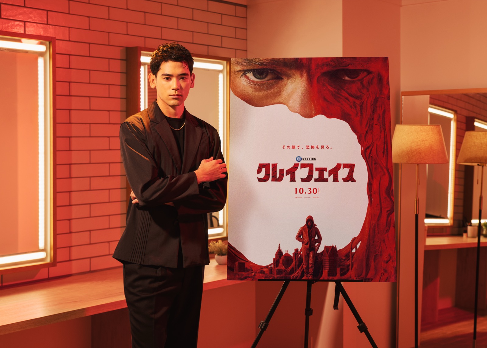『クレイフェイス』のポスターの横に立つUTA