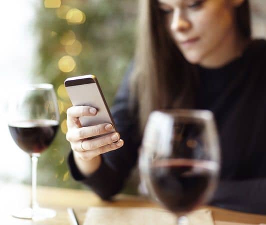 助けてドリンク「エンジェル・ショット」　バーでスマホをいじる女性